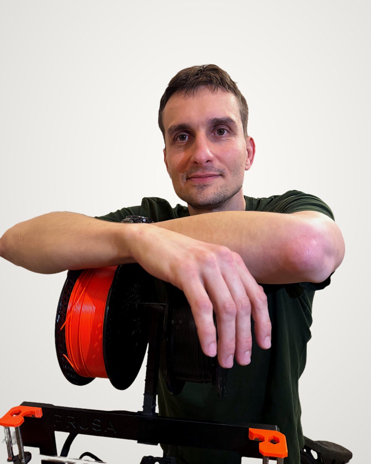 Michal Bláha opřený o 3D tiskárnu Prusa s cívkou filamentu